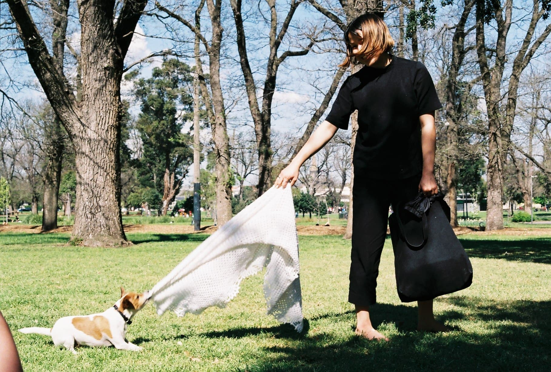 Two people playing with a dog in a park.