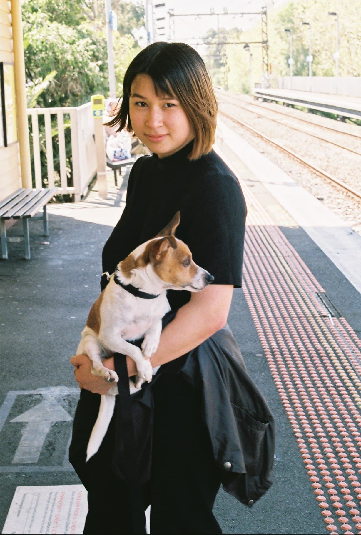 A person seated beside a sunlit wall.