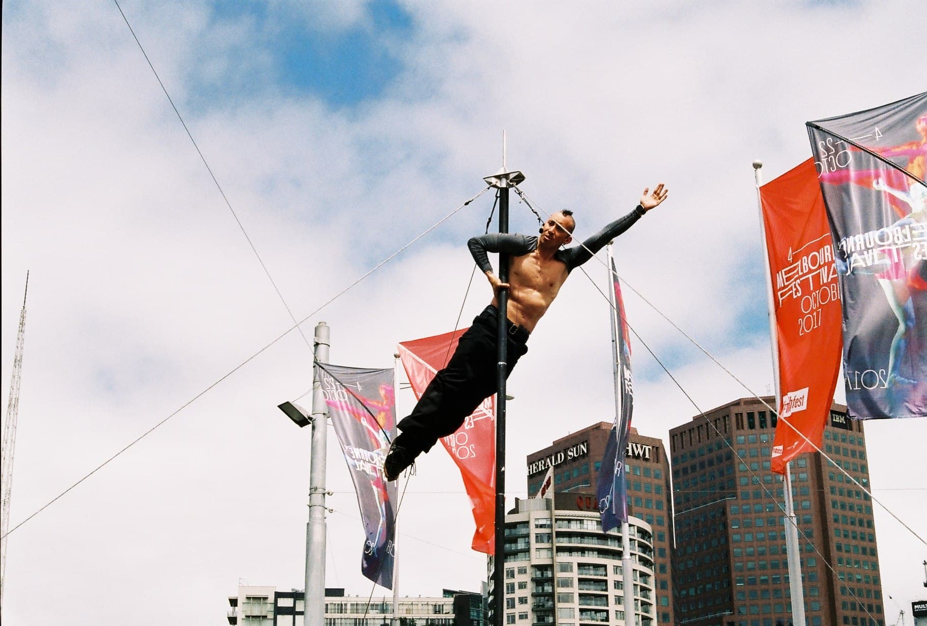 A person posing beside street flags against a city skyline.