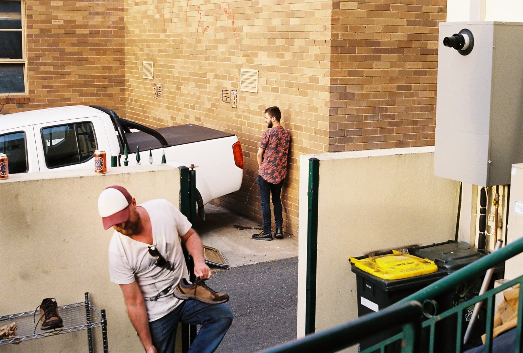 People beside parked vehicles in an urban alley.