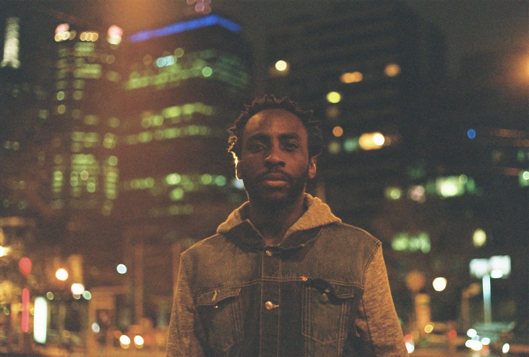 Night-time portrait with bright city lights behind.