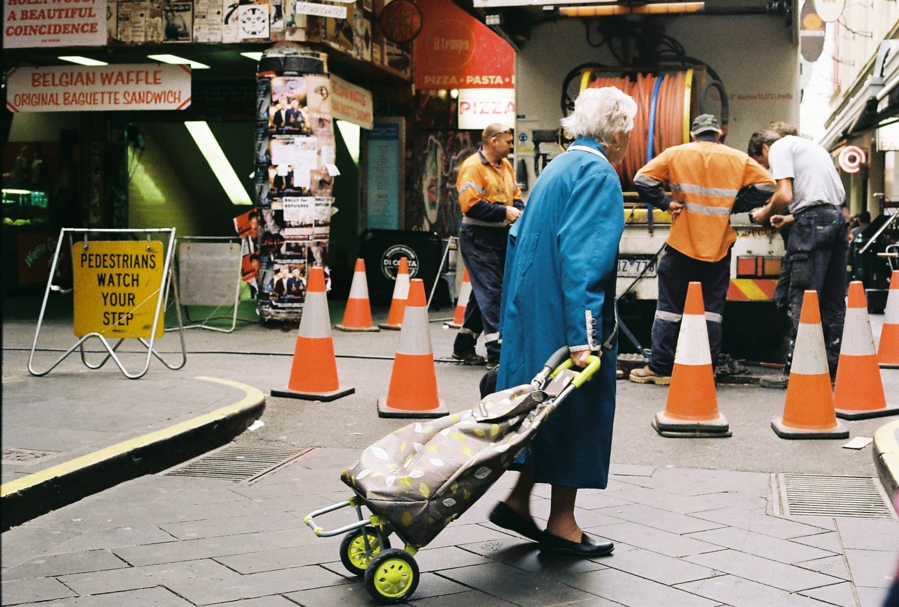 A person pushing a pram along a busy street.