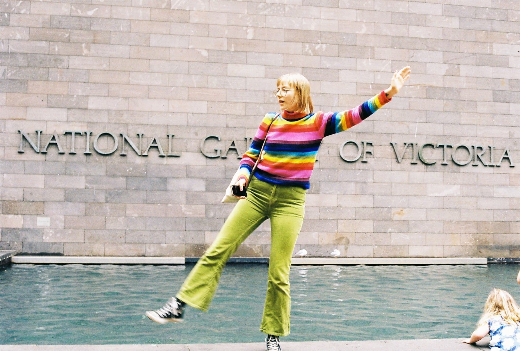 A person posing beside the National Gallery of Victoria sign.