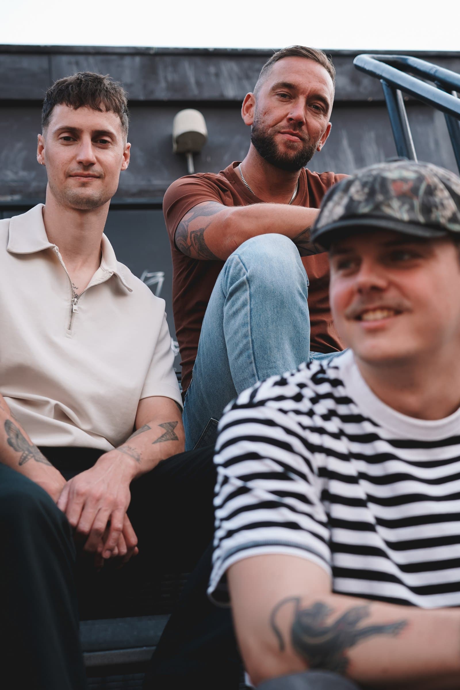 Close group portrait of Corleone on an outdoor staircase, with one band member in the foreground.