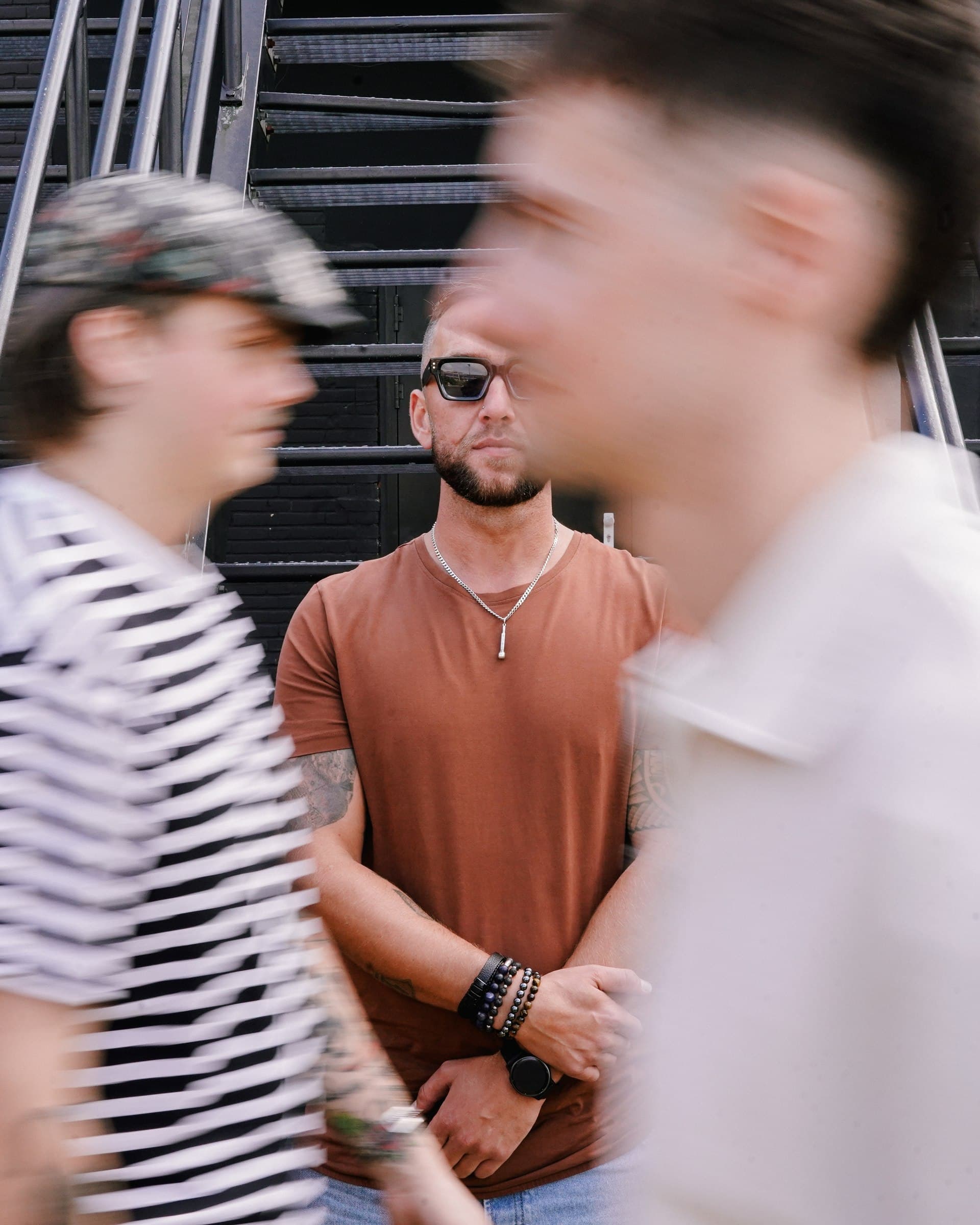 A Corleone band member in focus against a staircase while two others move past in the foreground.