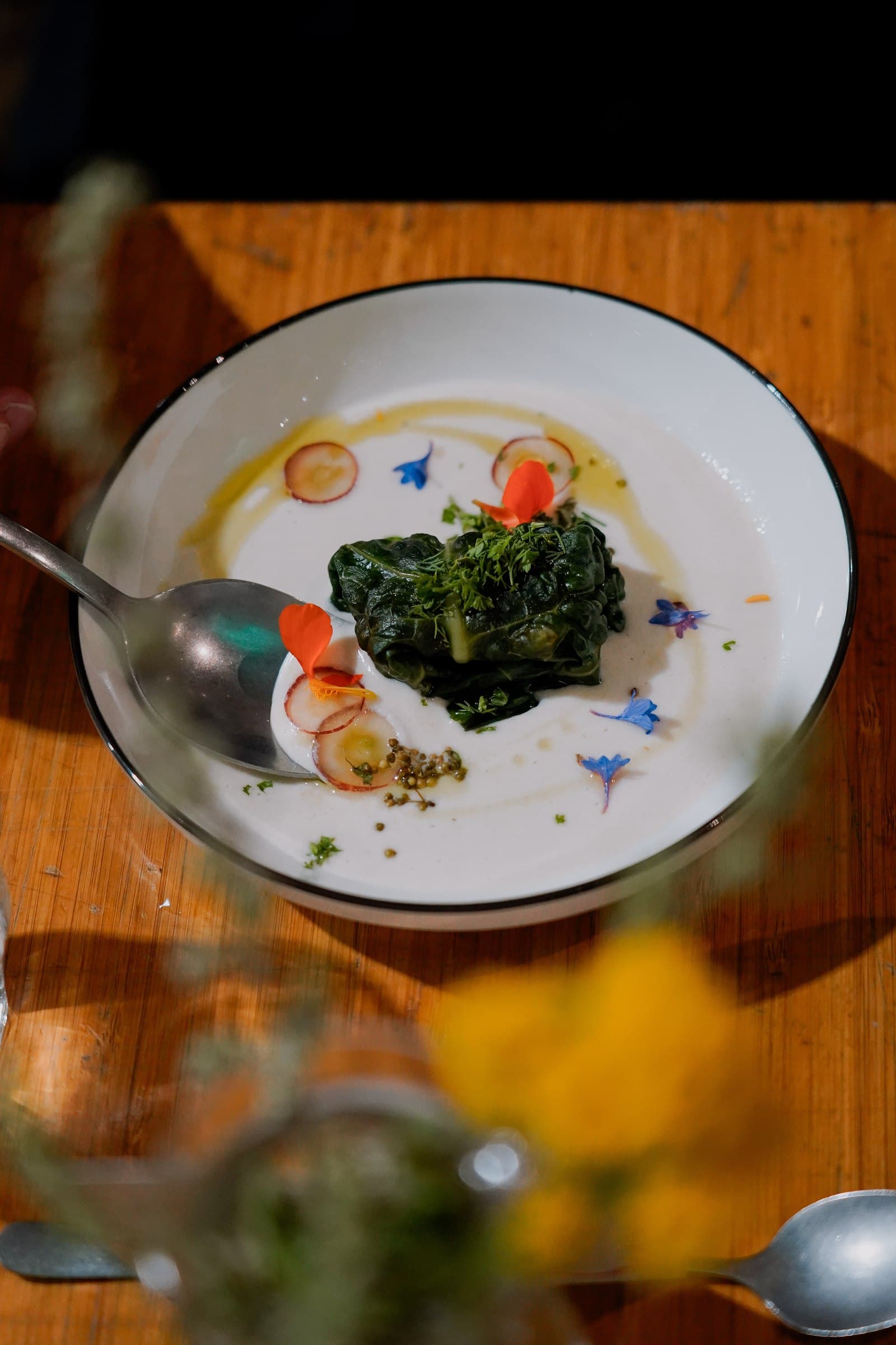 A plated dish with vegetables and colourful garnishes on a wooden table.