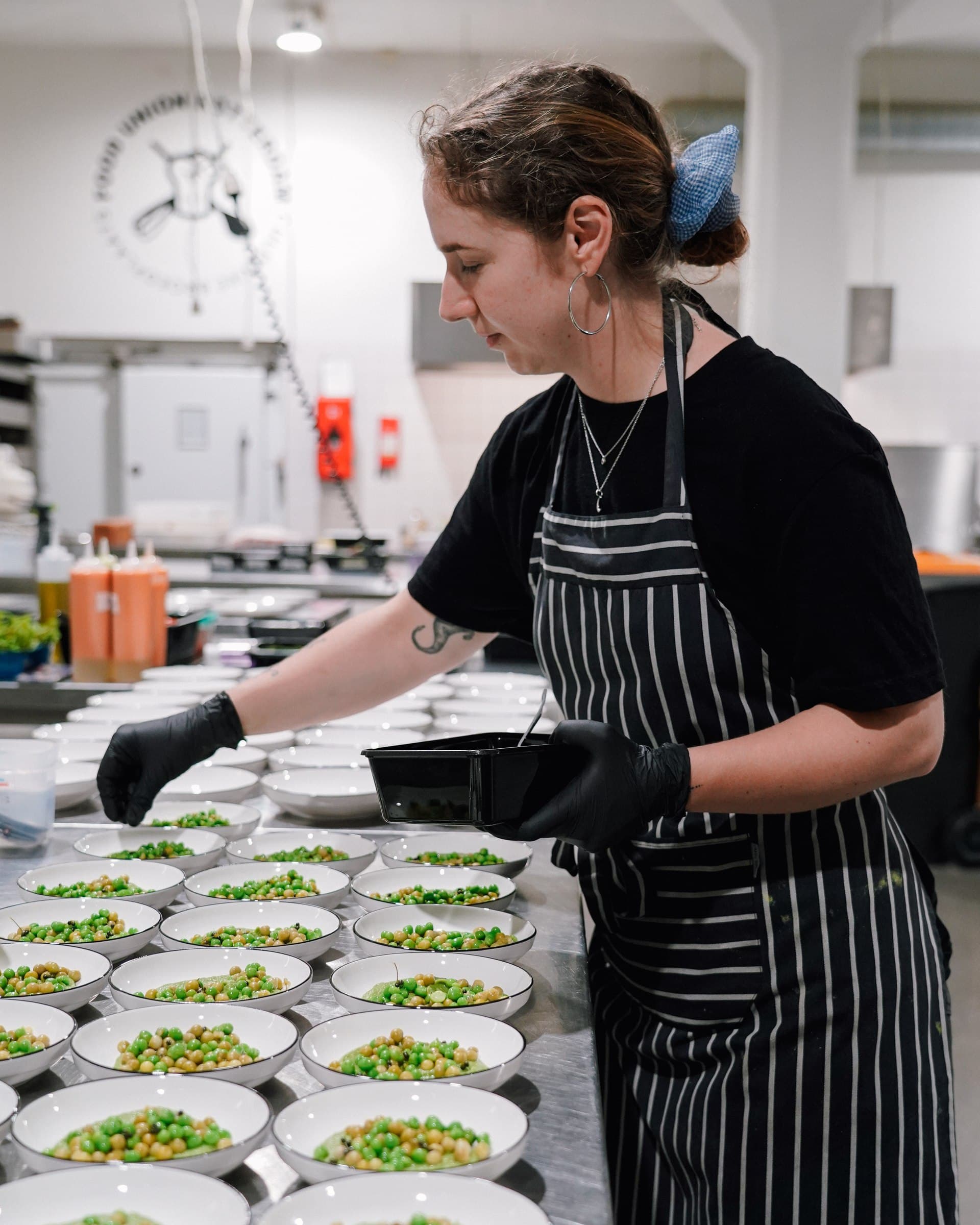 A chef in a striped apron plating dishes in the kitchen.