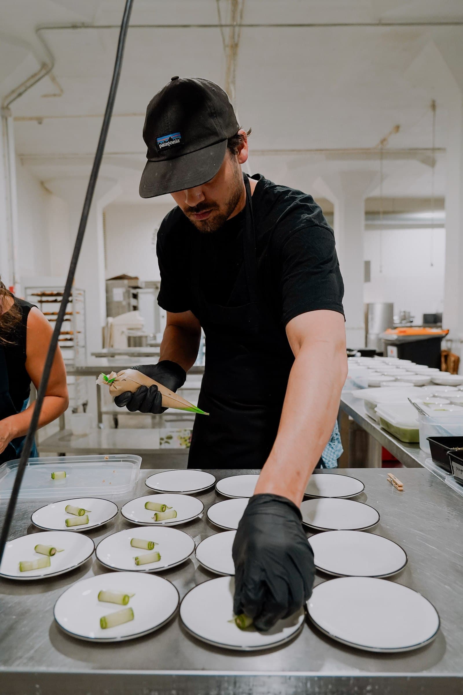 A chef in black preparing a row of plates in the kitchen.