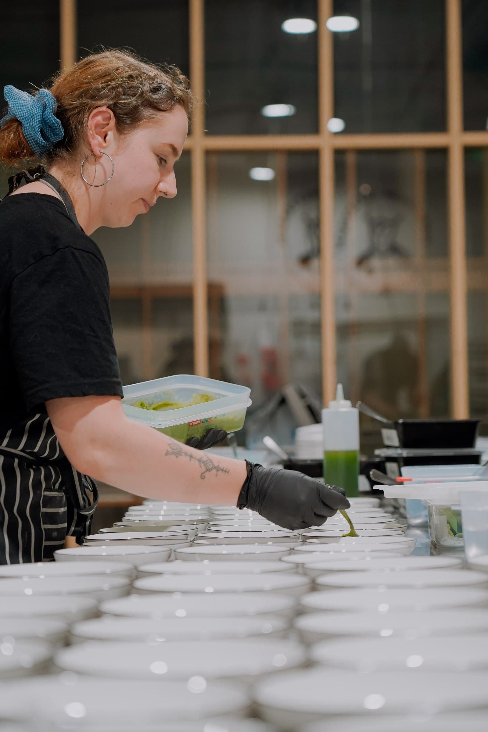 A chef working beside rows of plates during dinner preparation.