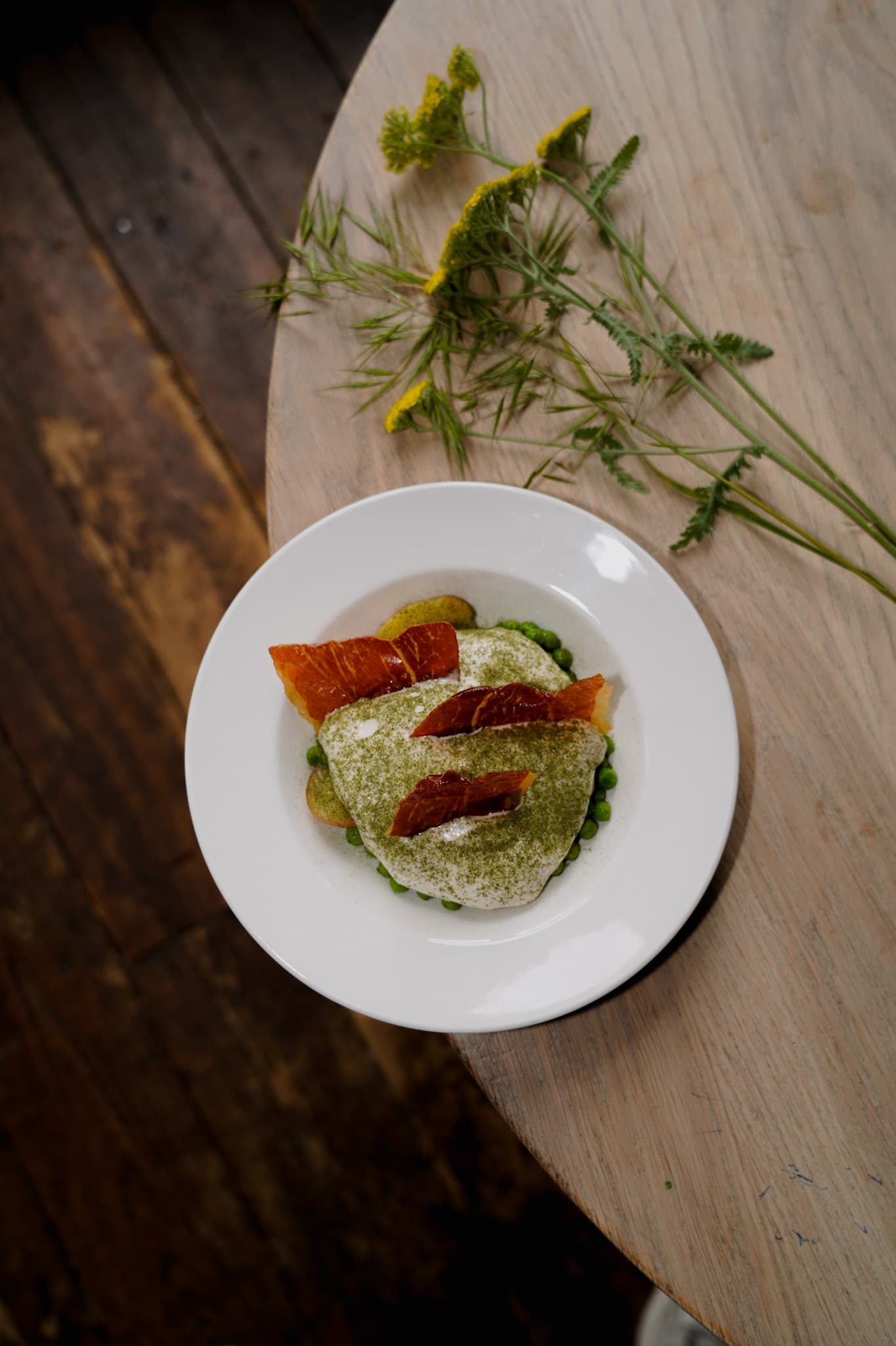 A small plated dish with green garnish on a wooden table.