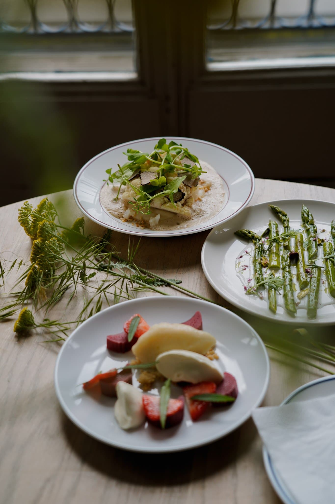 Plated dishes on a wooden table beside a curtain.