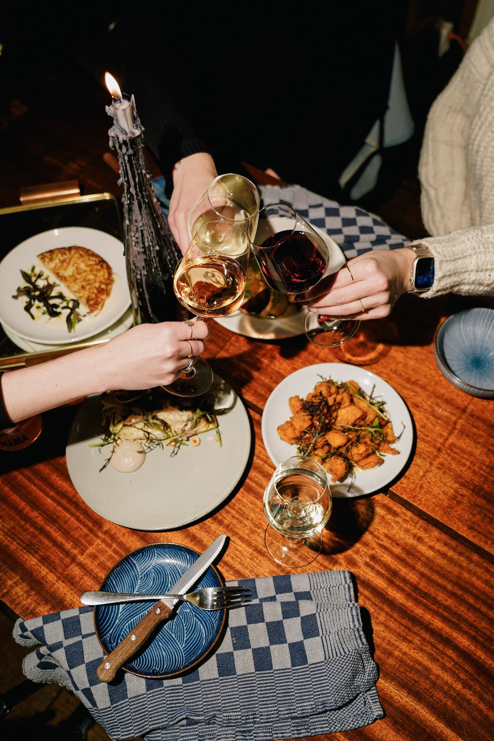 A colourful shared meal with plates and drinks, viewed from above.