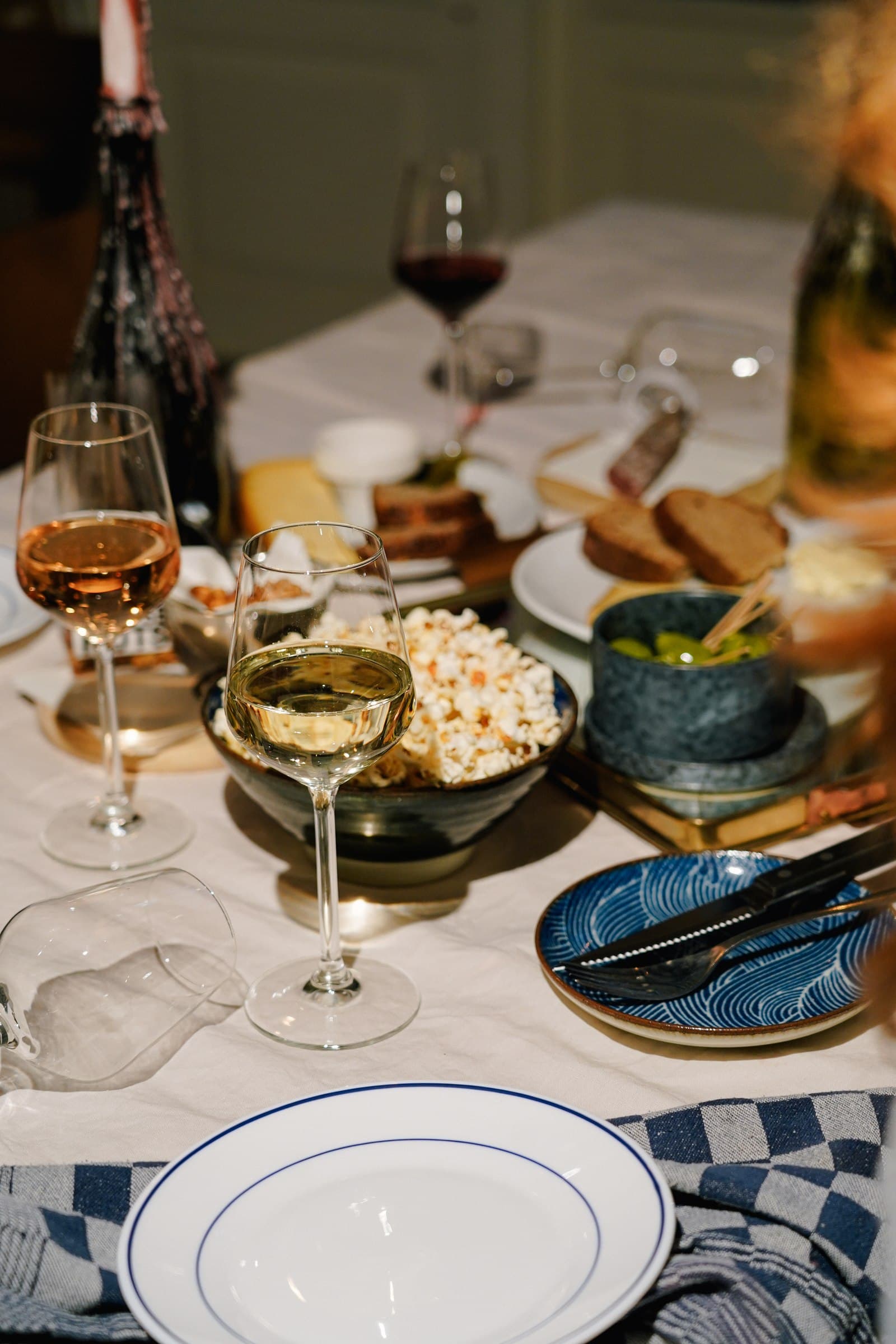 A table set with plates, drinks, candles and a wine bottle.