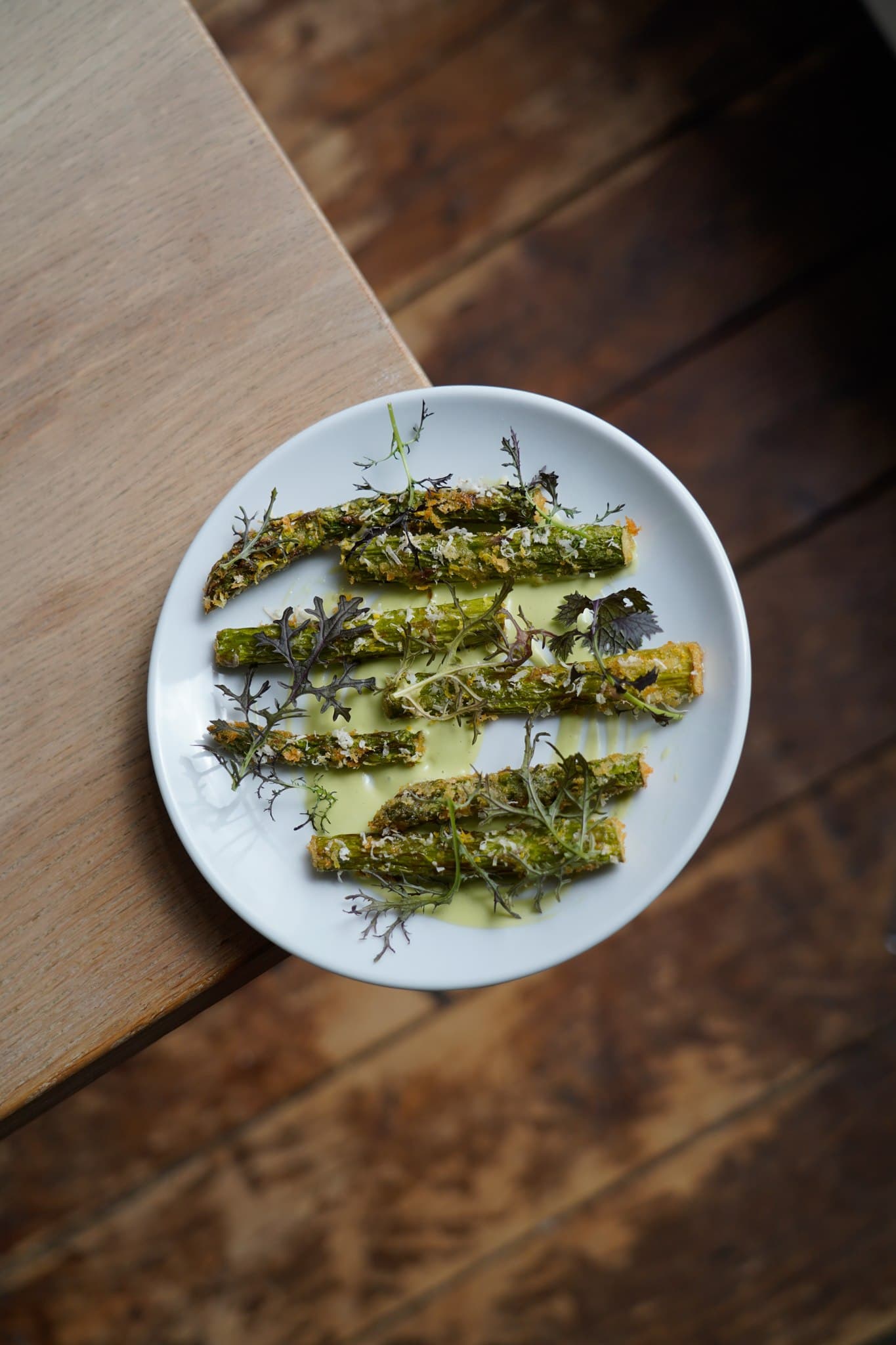 Green vegetables arranged on a white plate with cutlery nearby.
