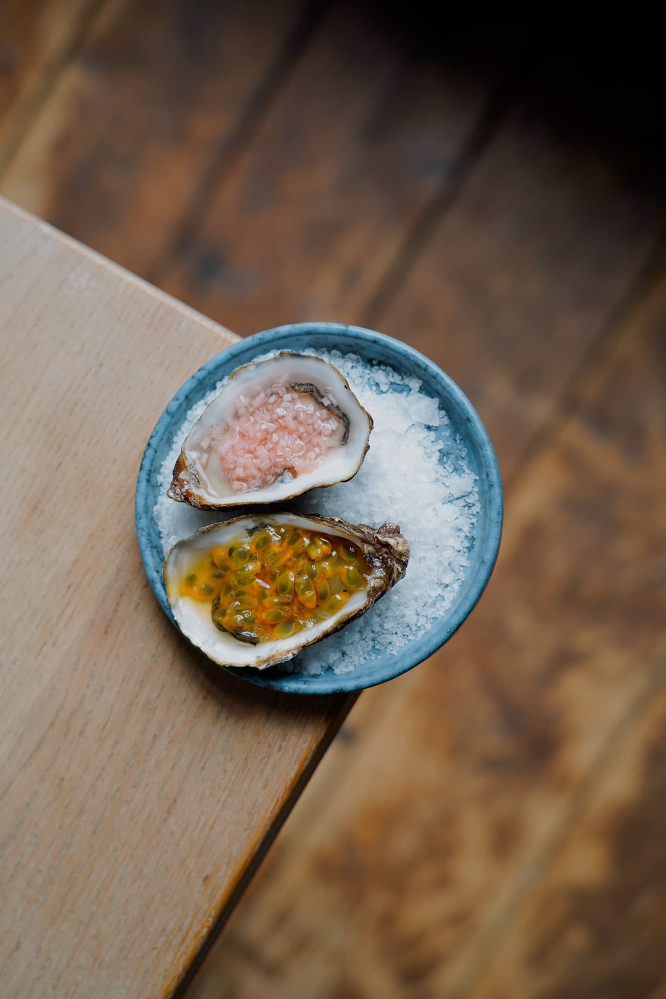 A small blue plate holding a yellow dish on a wooden tabletop.