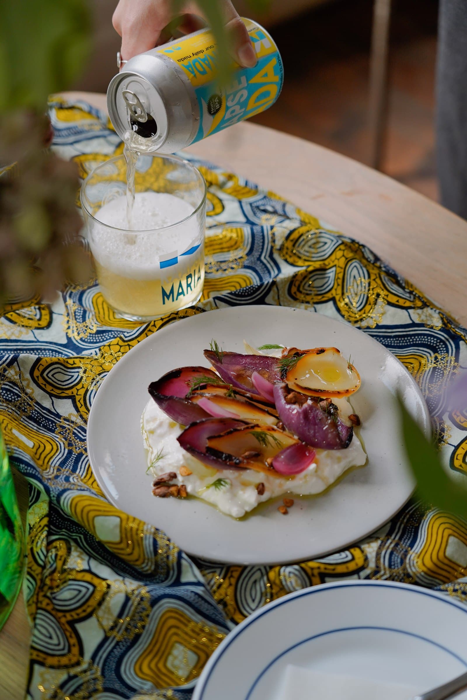 A plate of food and drinks on a patterned tablecloth.