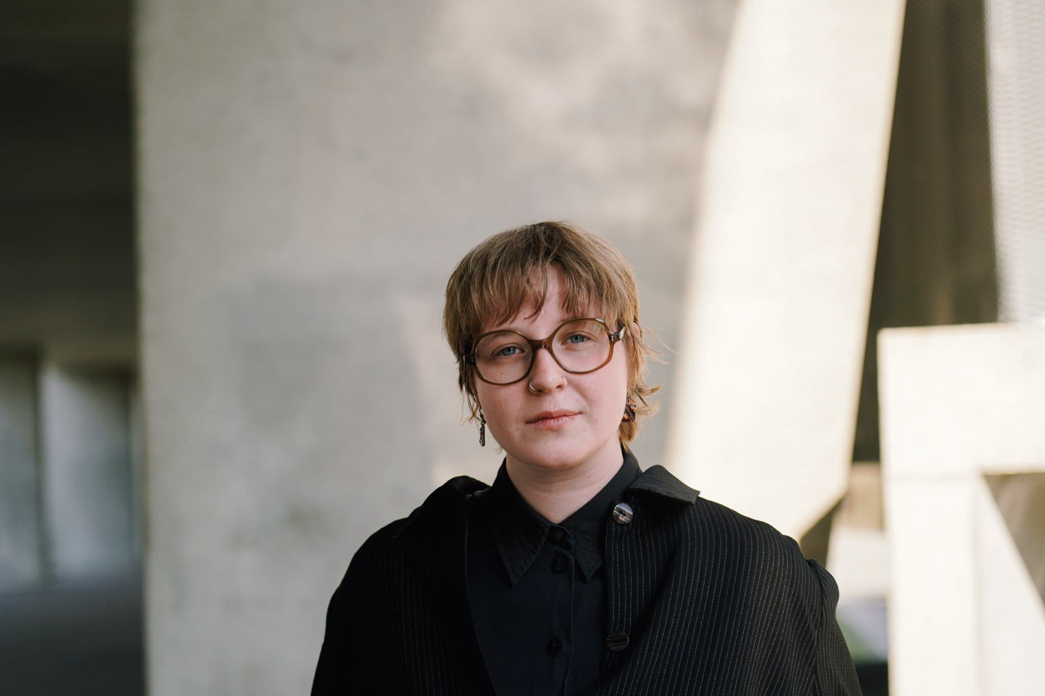 Portrait beside a sunlit concrete pillar.