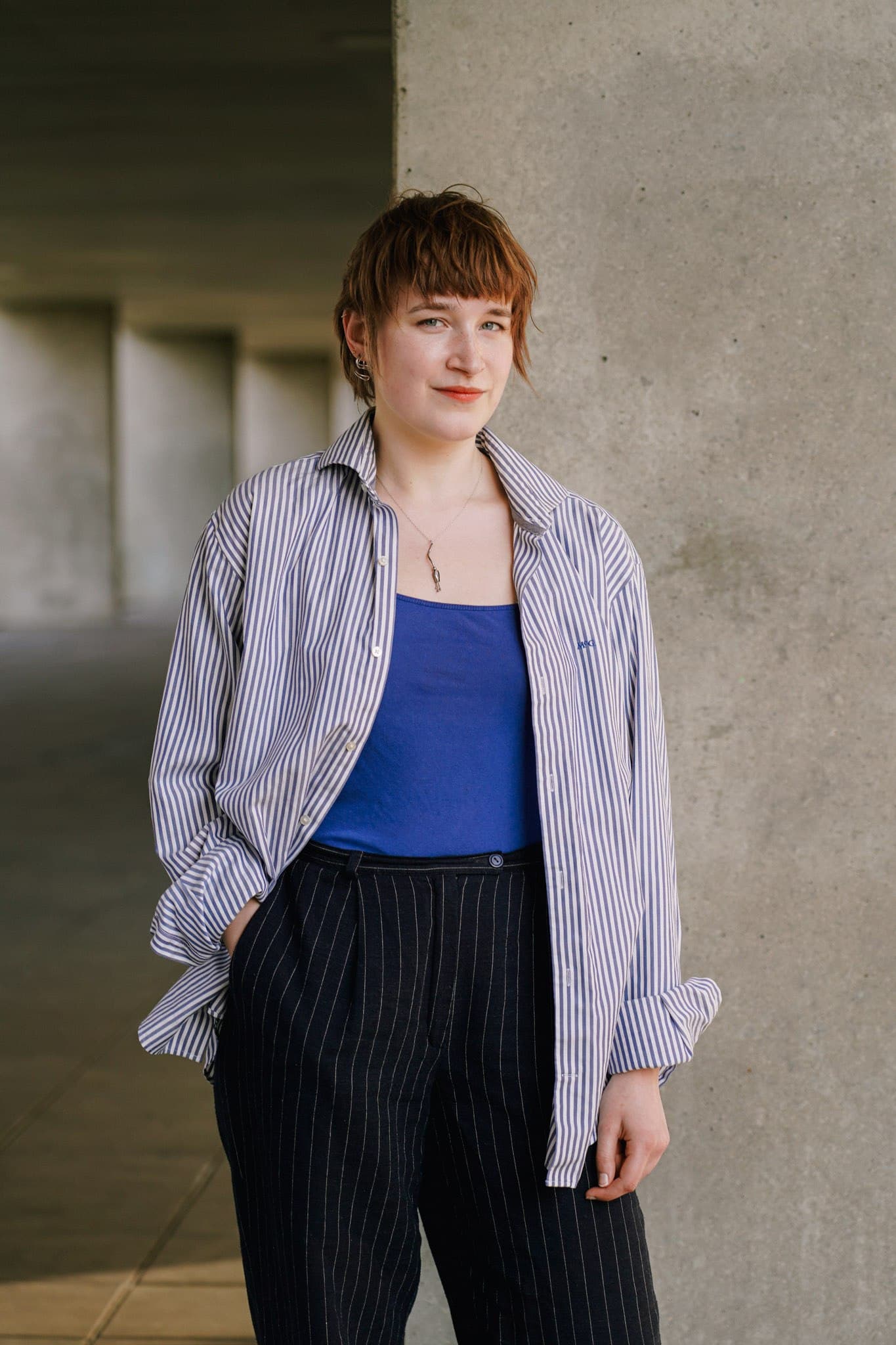 Full-length portrait in a lilac jacket and blue top.