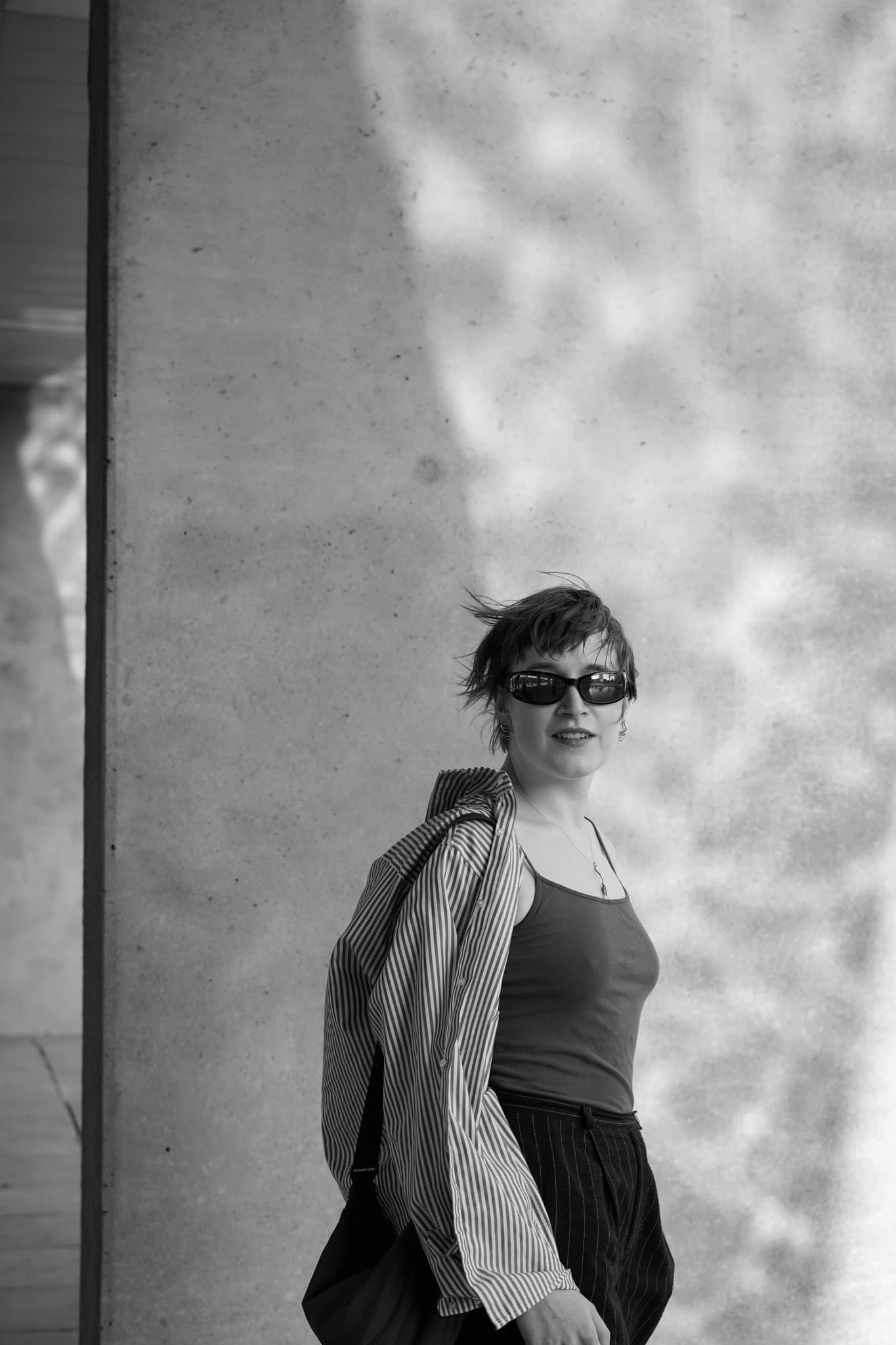 Black-and-white portrait against a wall patterned with shadows.