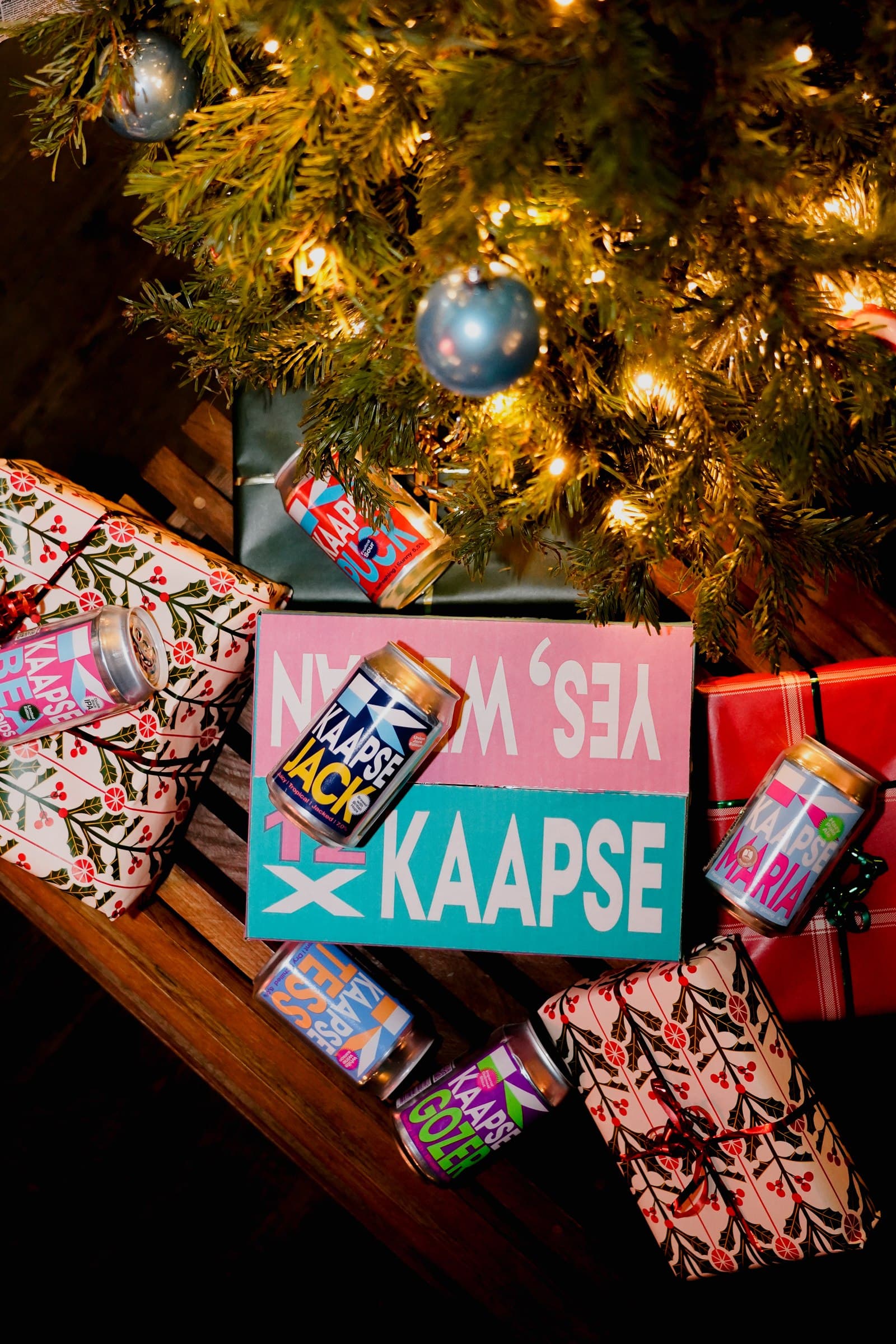 A boxed selection of Kaapse beers beside a decorated Christmas tree.