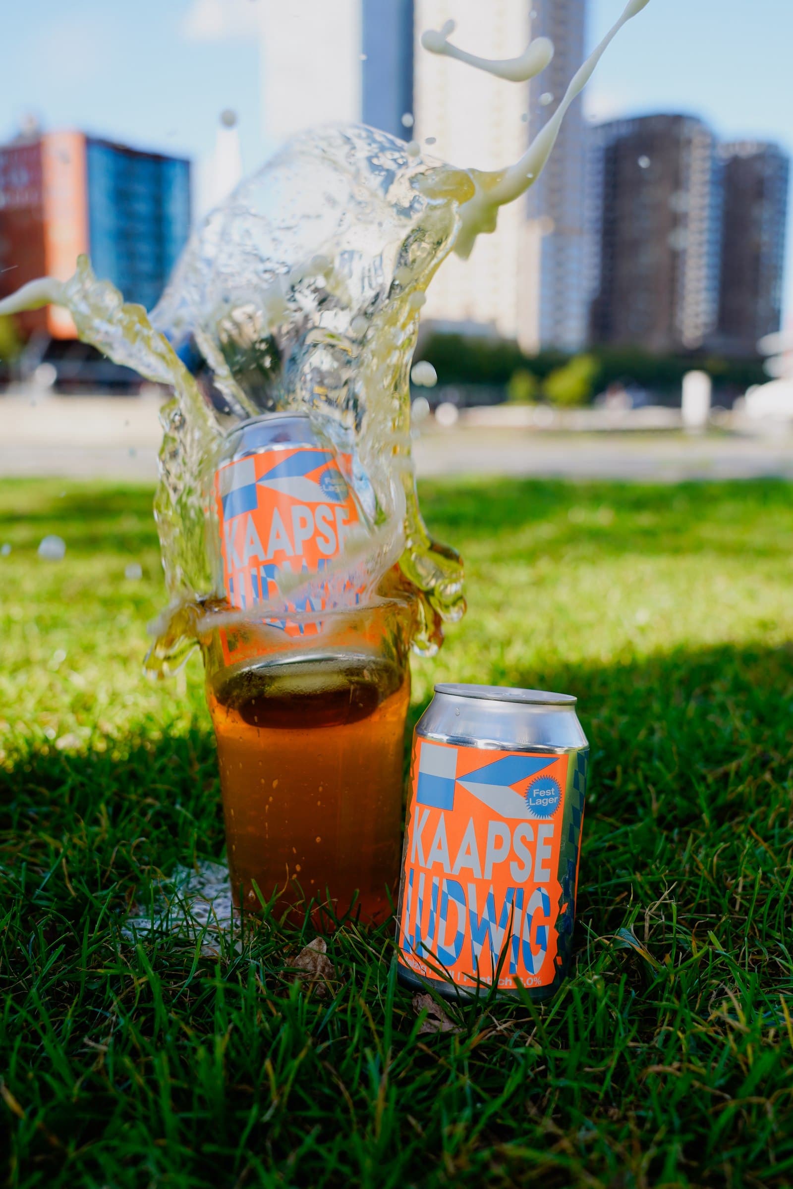 A drink being poured into a glass in the grass beside a beer can.