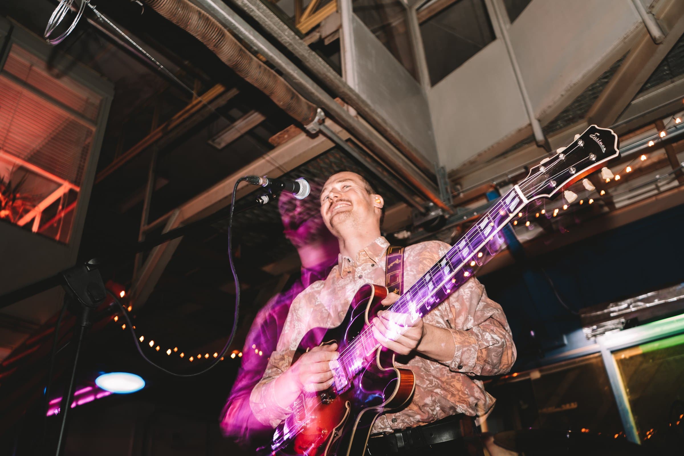 A guitarist playing beneath warm coloured stage lights.