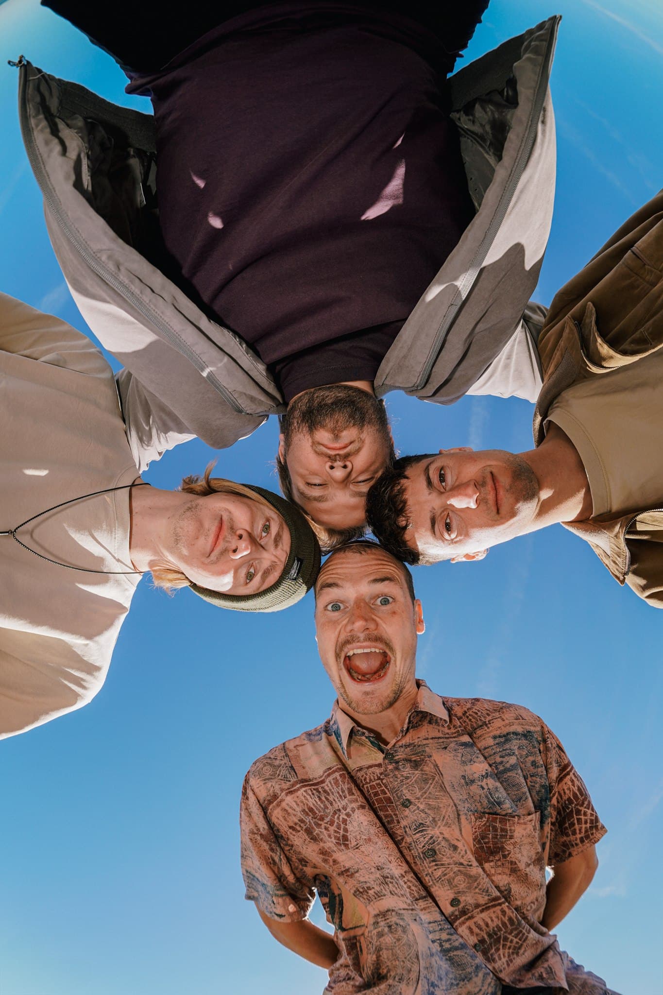 Four Rum for Breakfast band members looking down towards the camera against a blue sky.