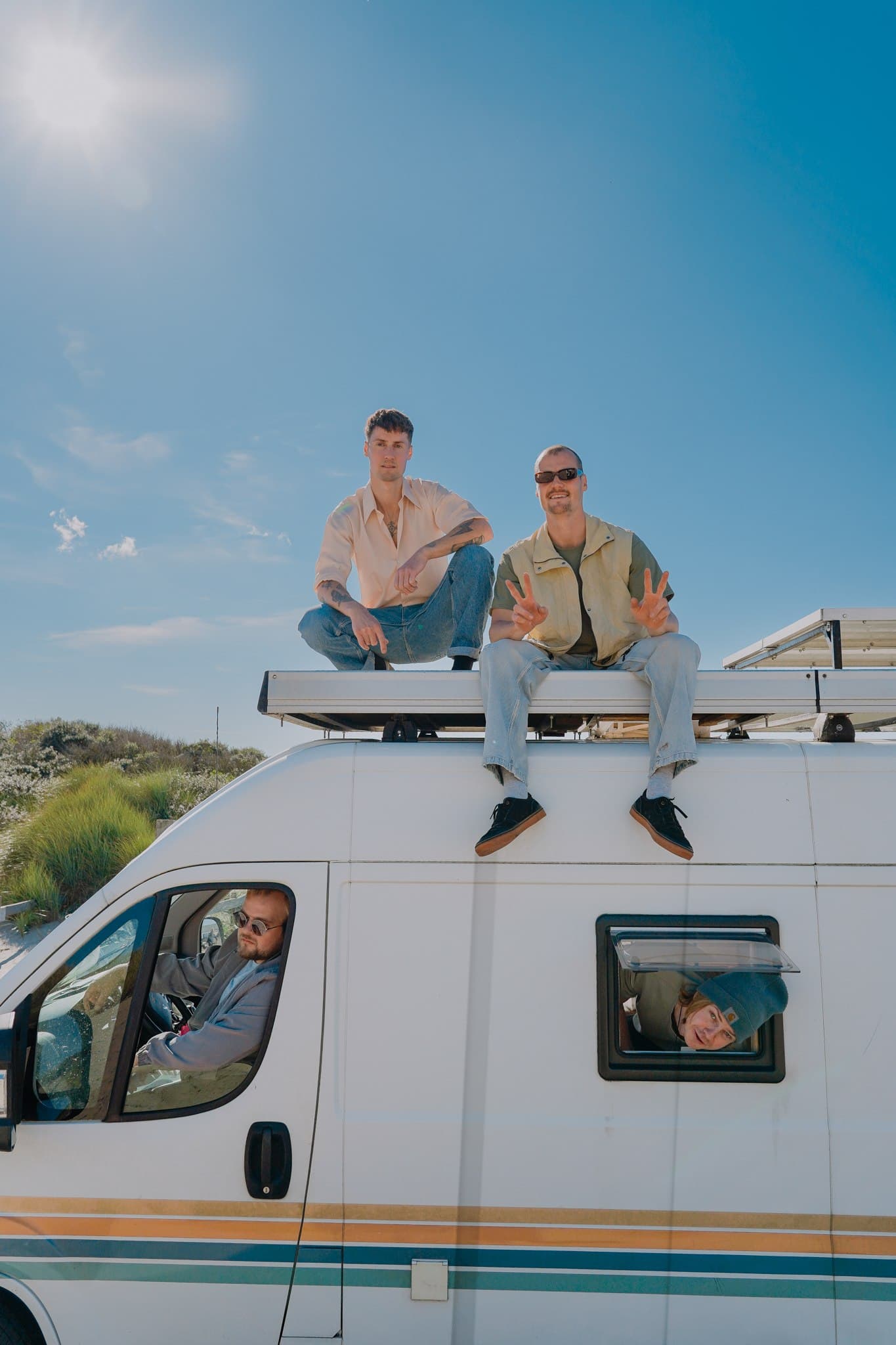 Rum for Breakfast posing on the roof and through the windows of a white campervan.