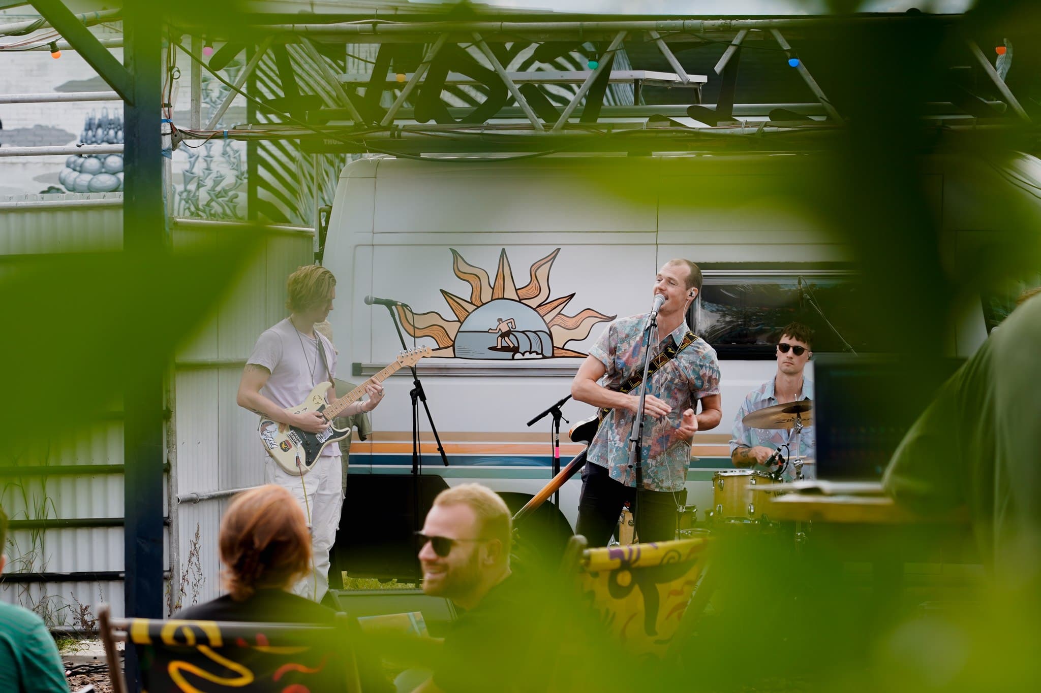 An outdoor band performance framed by green leaves.