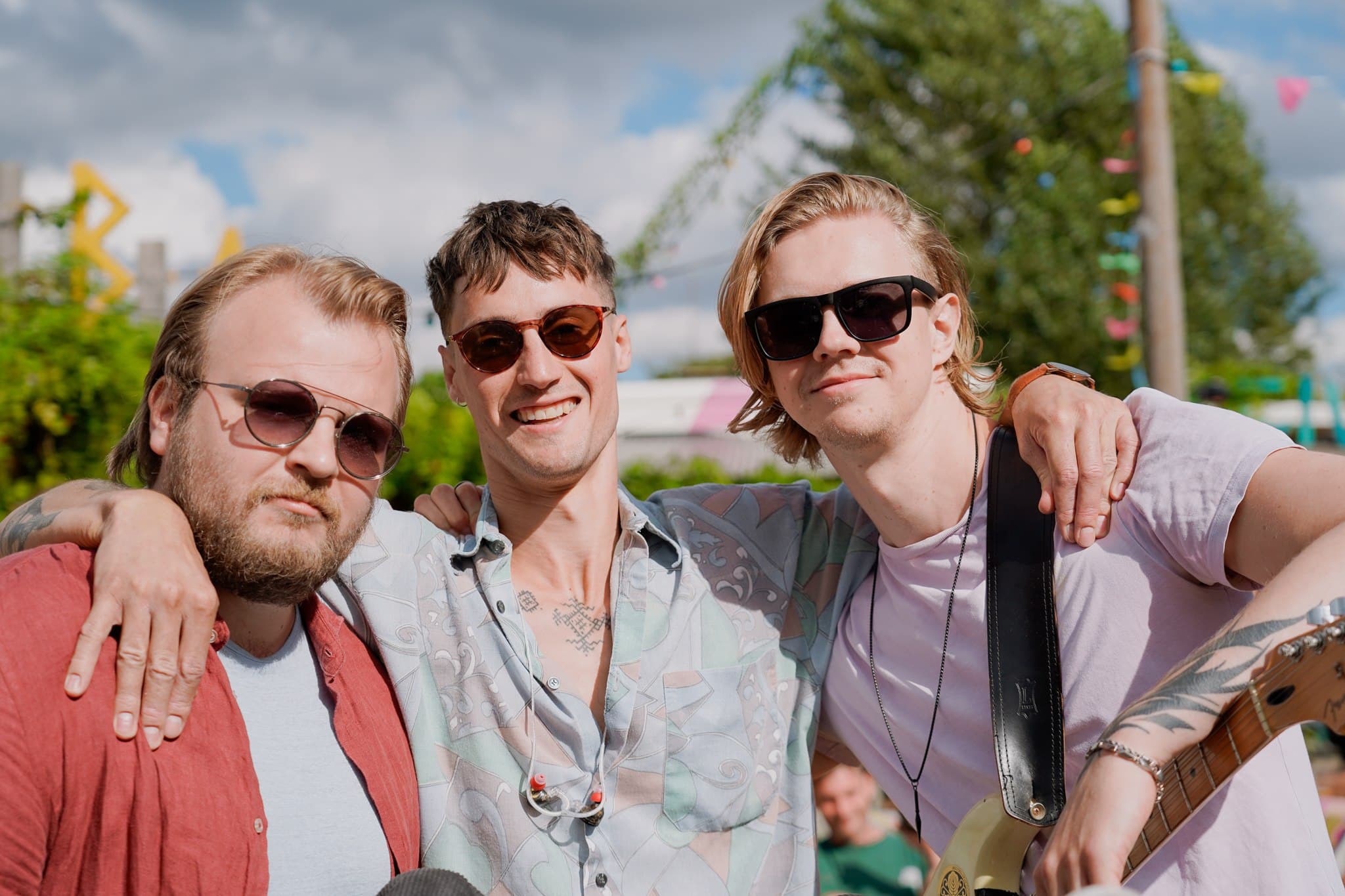 Three band members posing together outdoors.