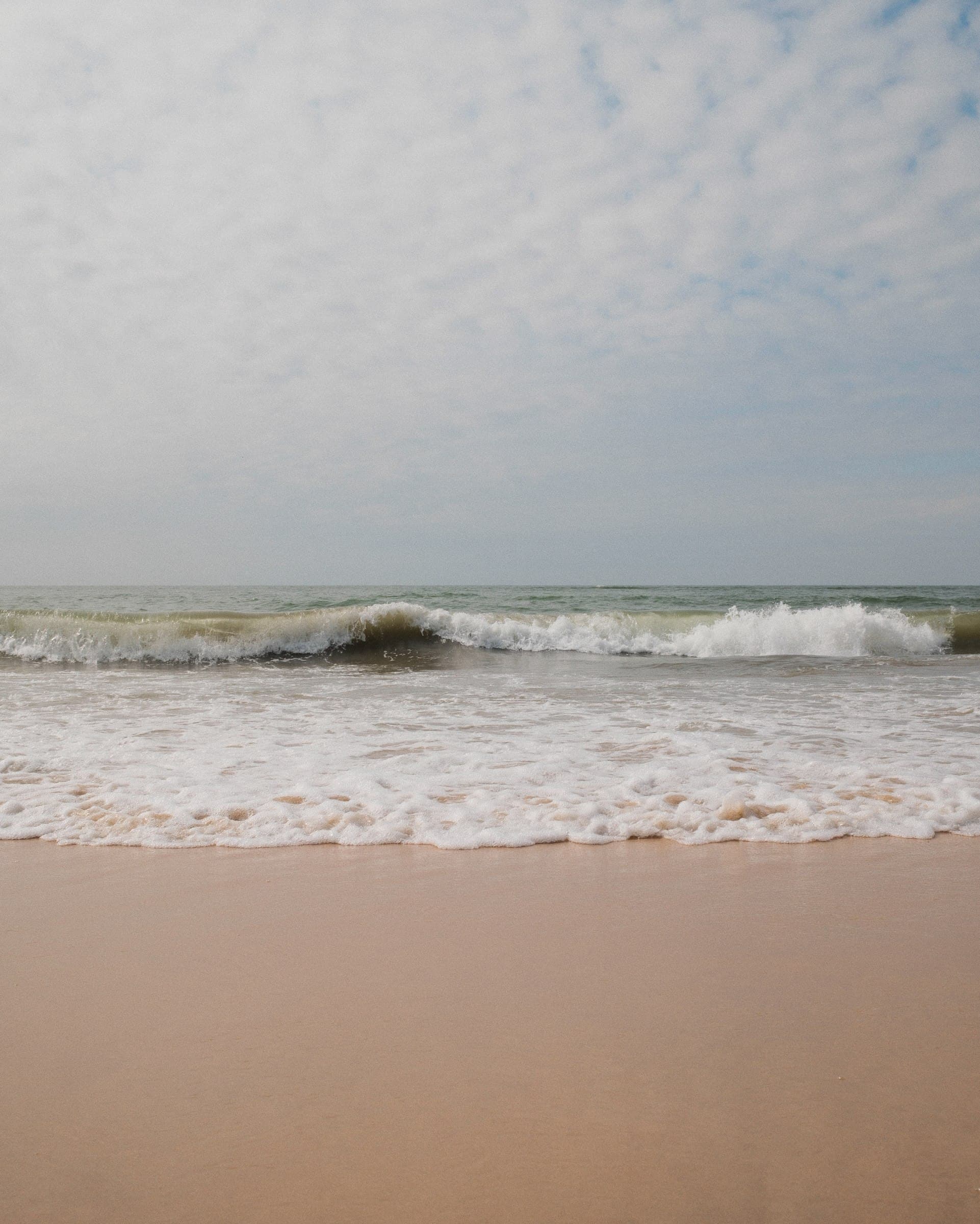 A breaking wave on a sandy beach.