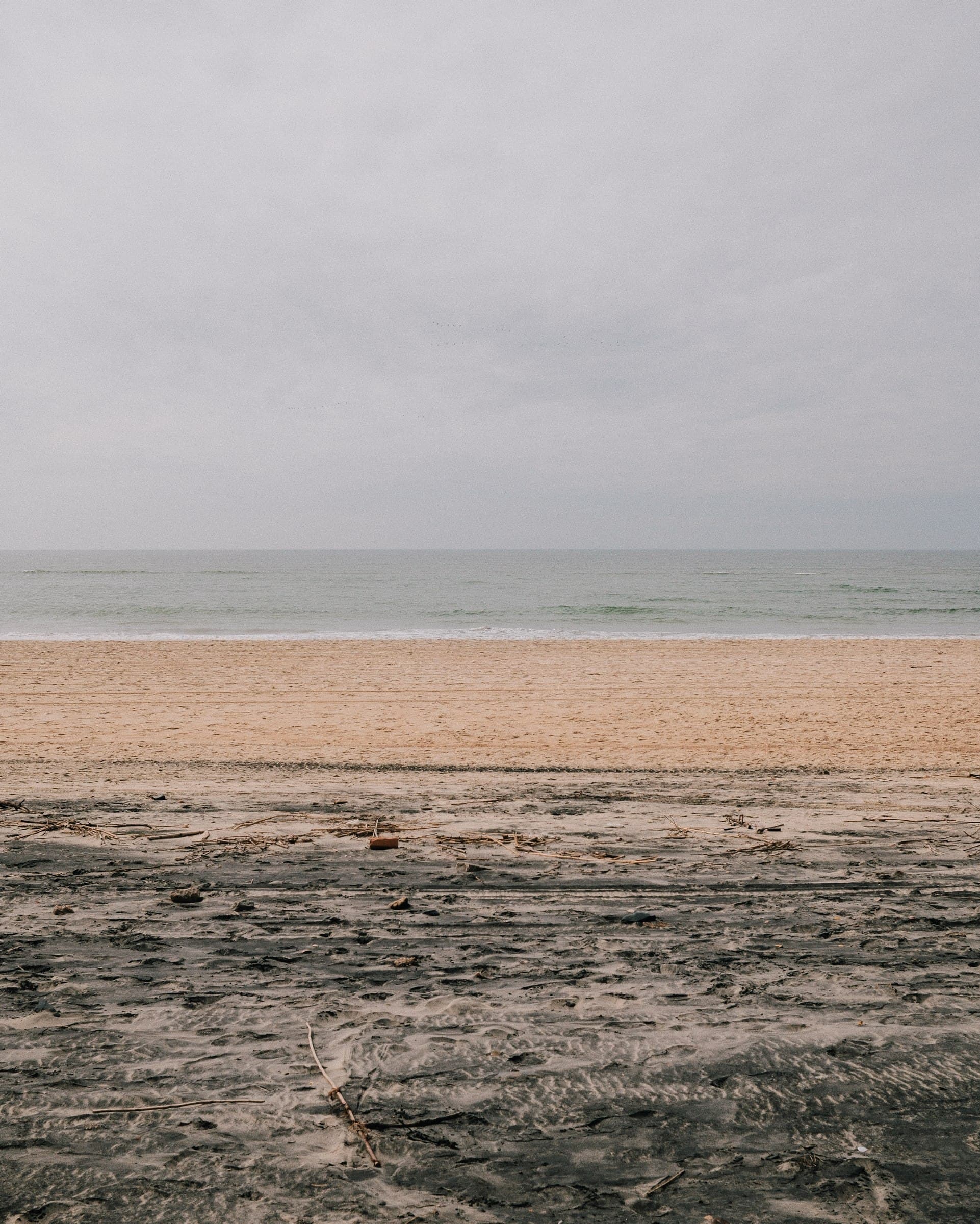 Wet sand and a band of sea beneath a grey sky.