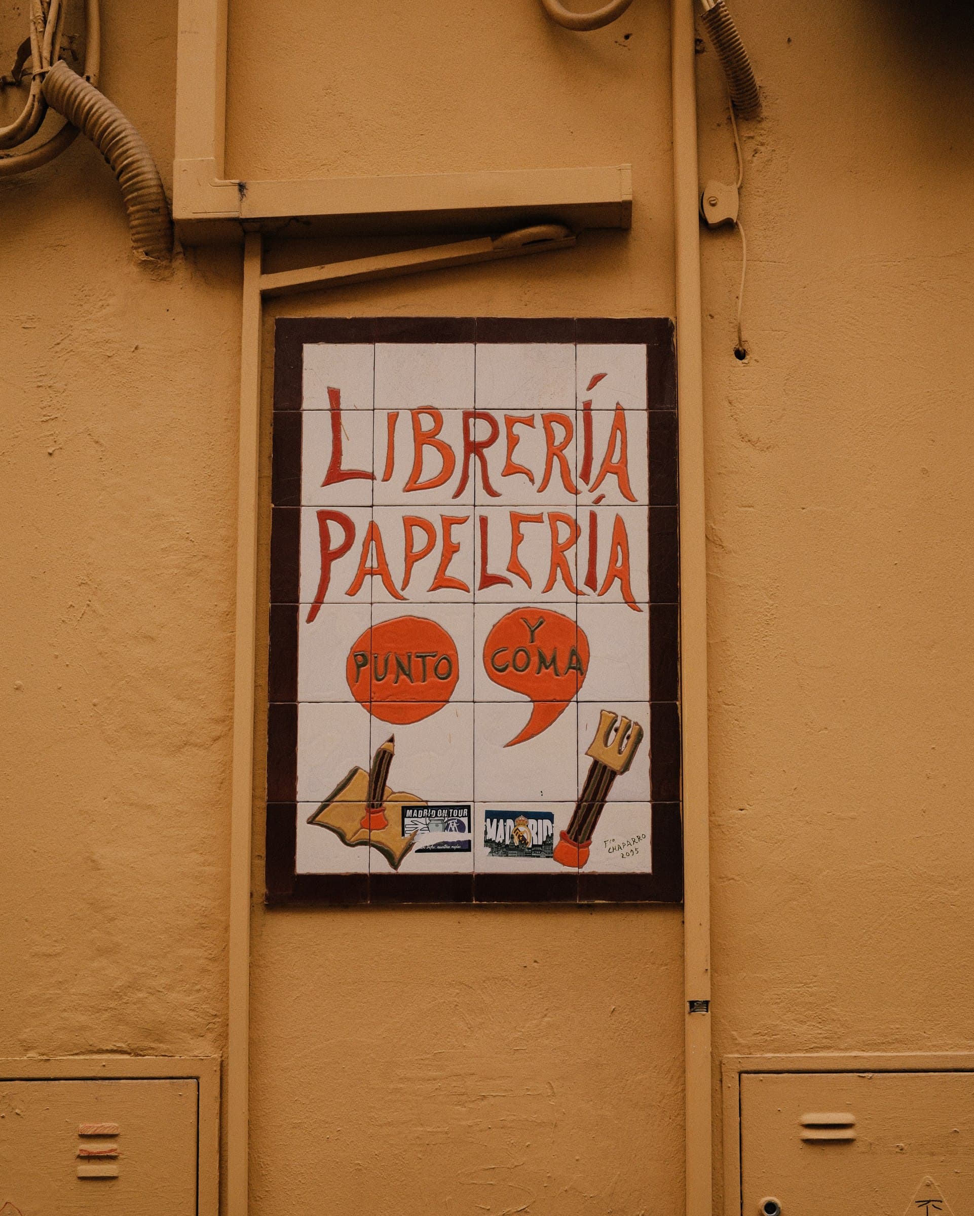 A colourful illustrated sign on an ochre facade.