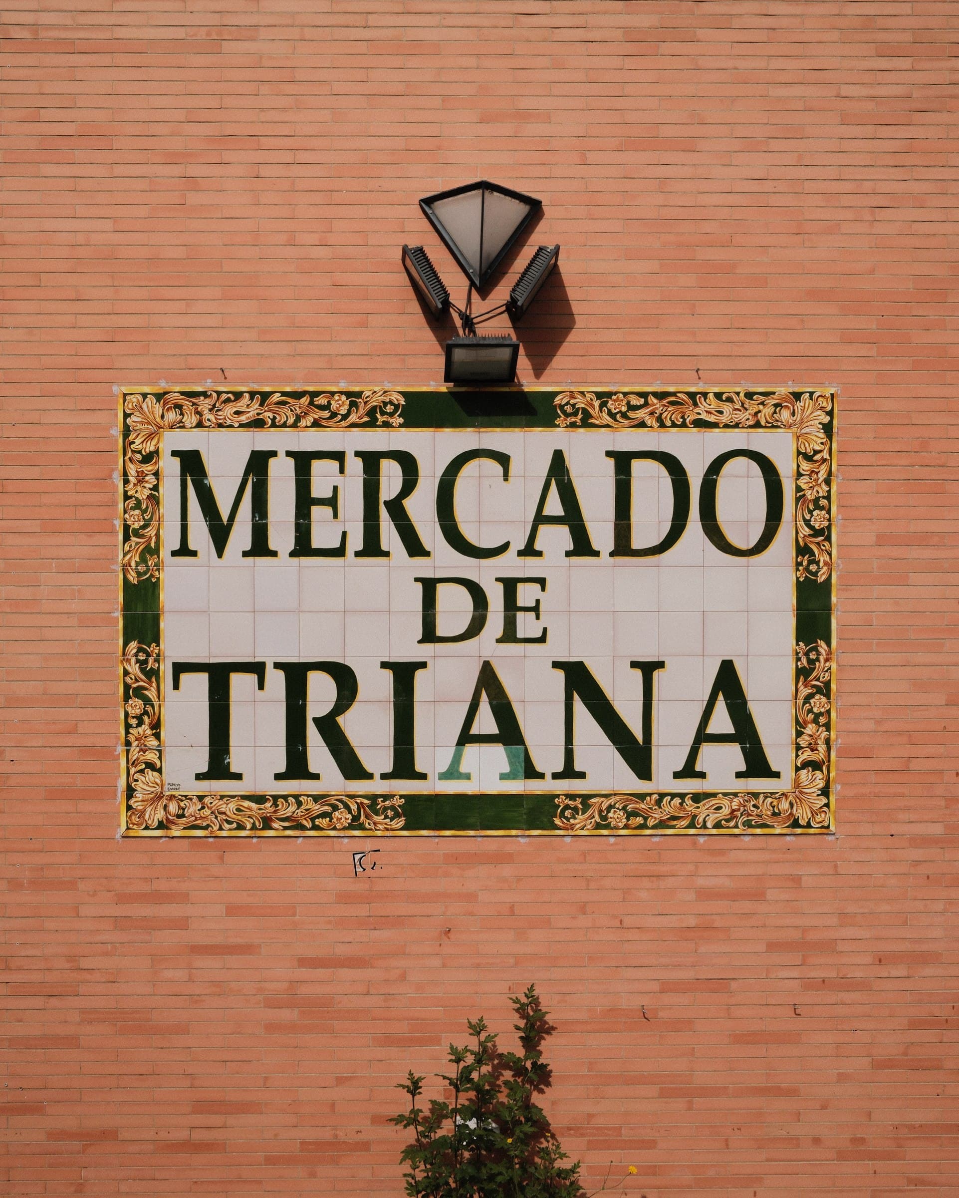 Mercado de Triana sign on a terracotta wall.