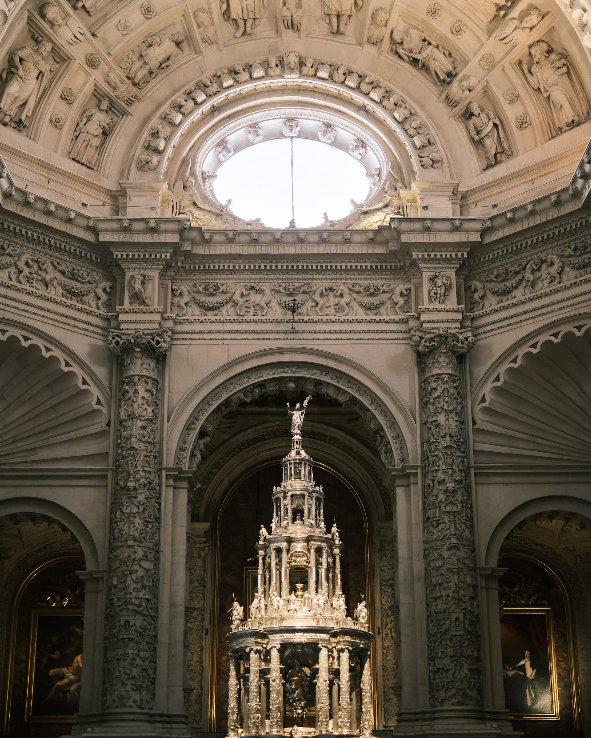 An ornate church interior with a vaulted ceiling and a luminous window.