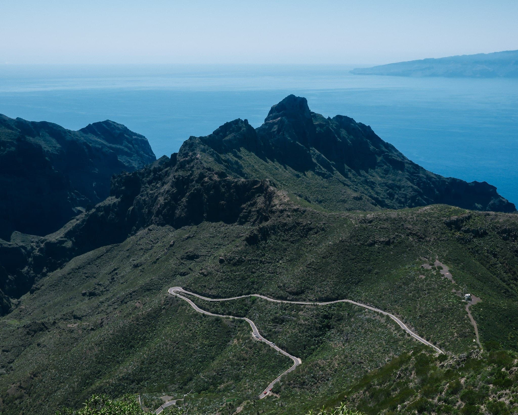 Winding path across green mountain ridges above the sea.