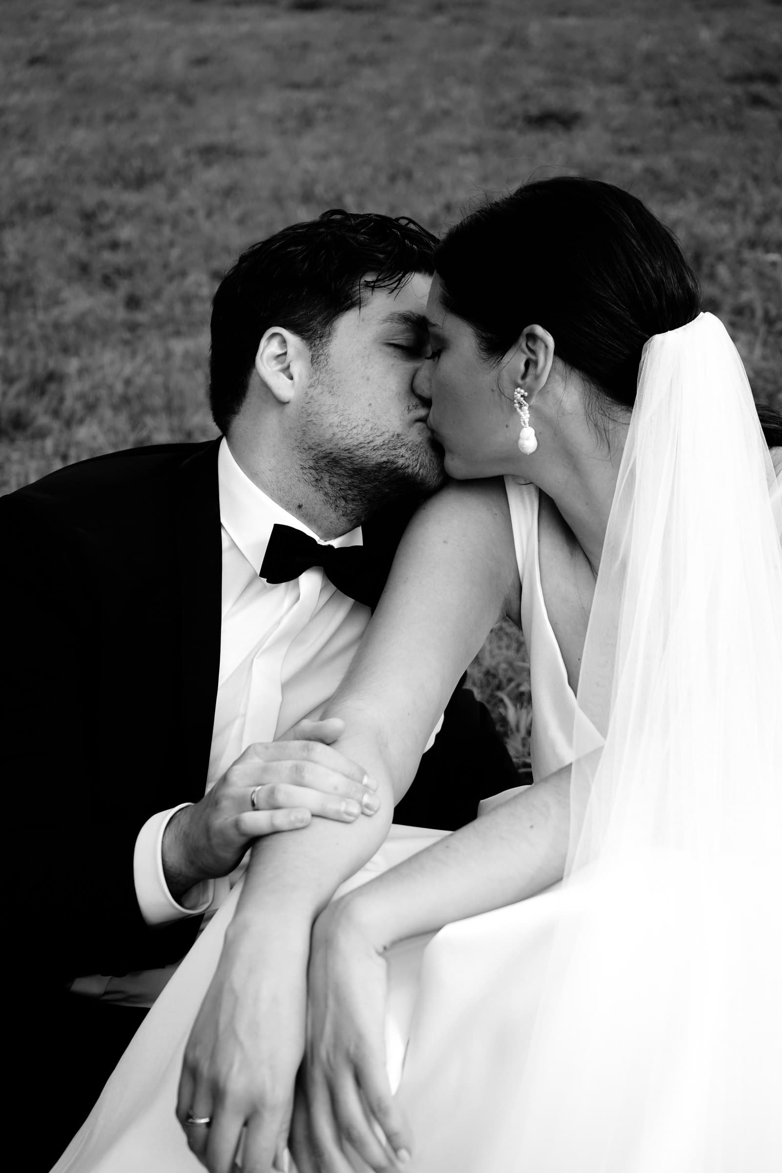 Black-and-white photograph of the wedding couple kissing.