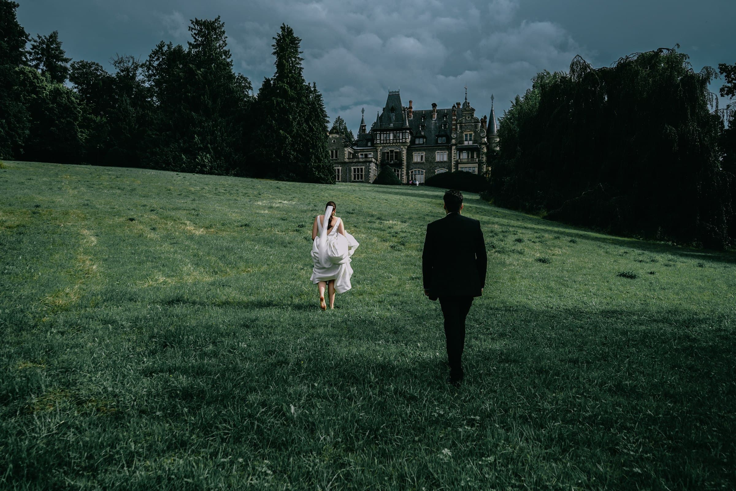 The wedding couple walking across a lawn towards one another.