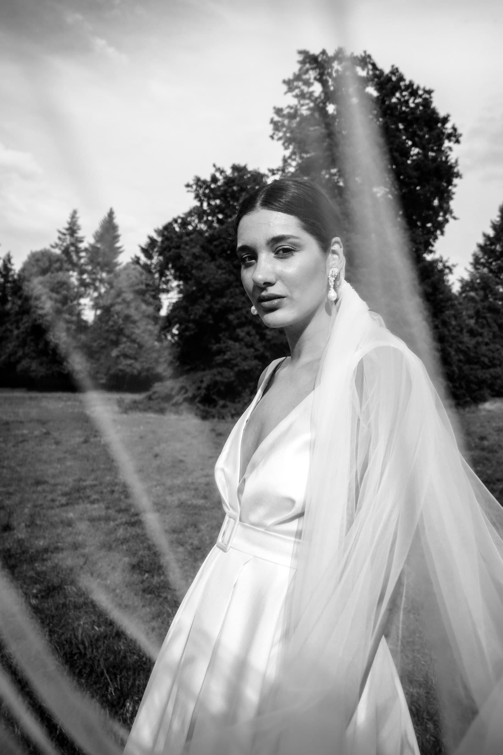 Black-and-white portrait of the bride with her veil outdoors.