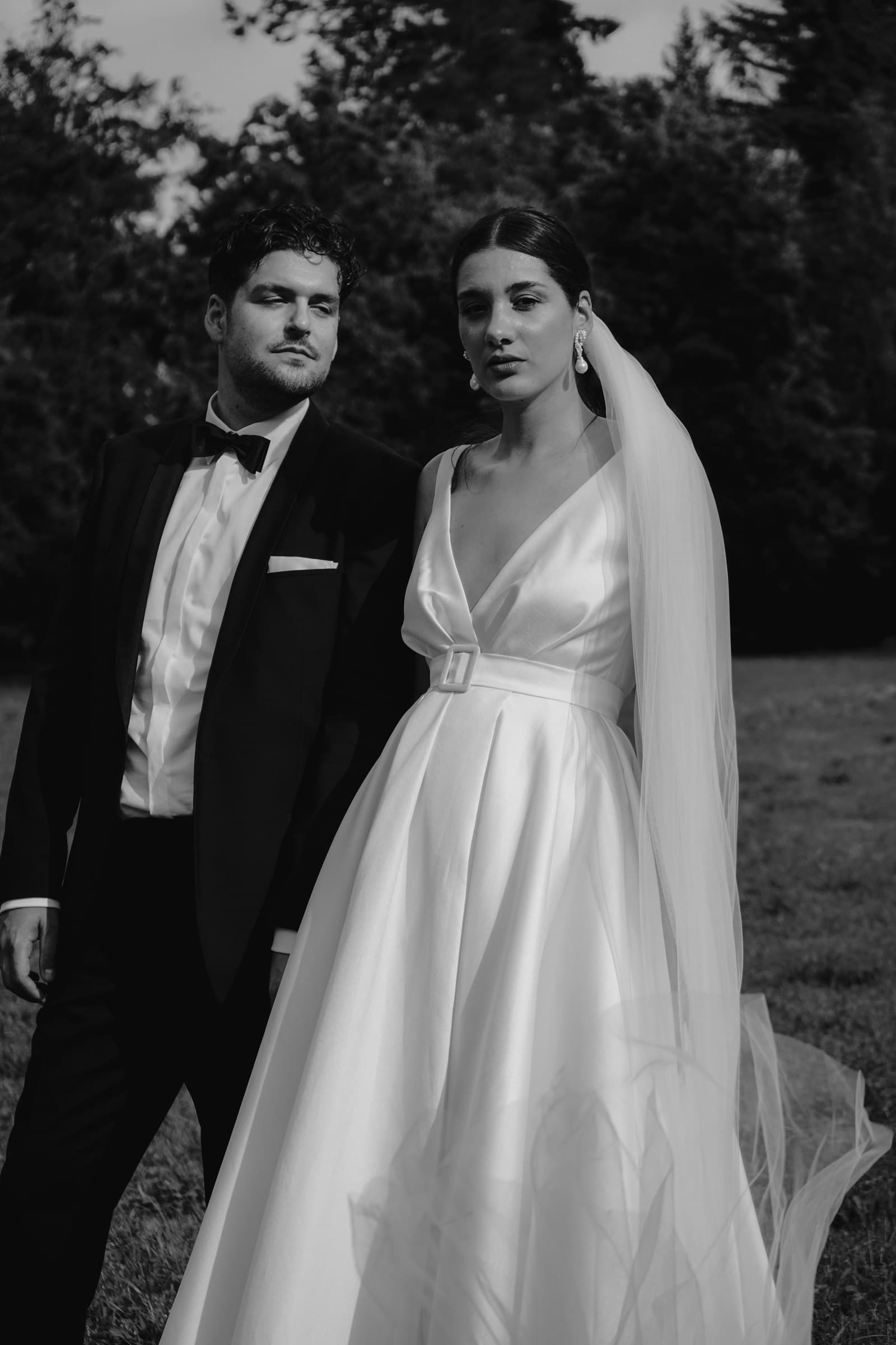 Black-and-white portrait of the wedding couple standing together outdoors.