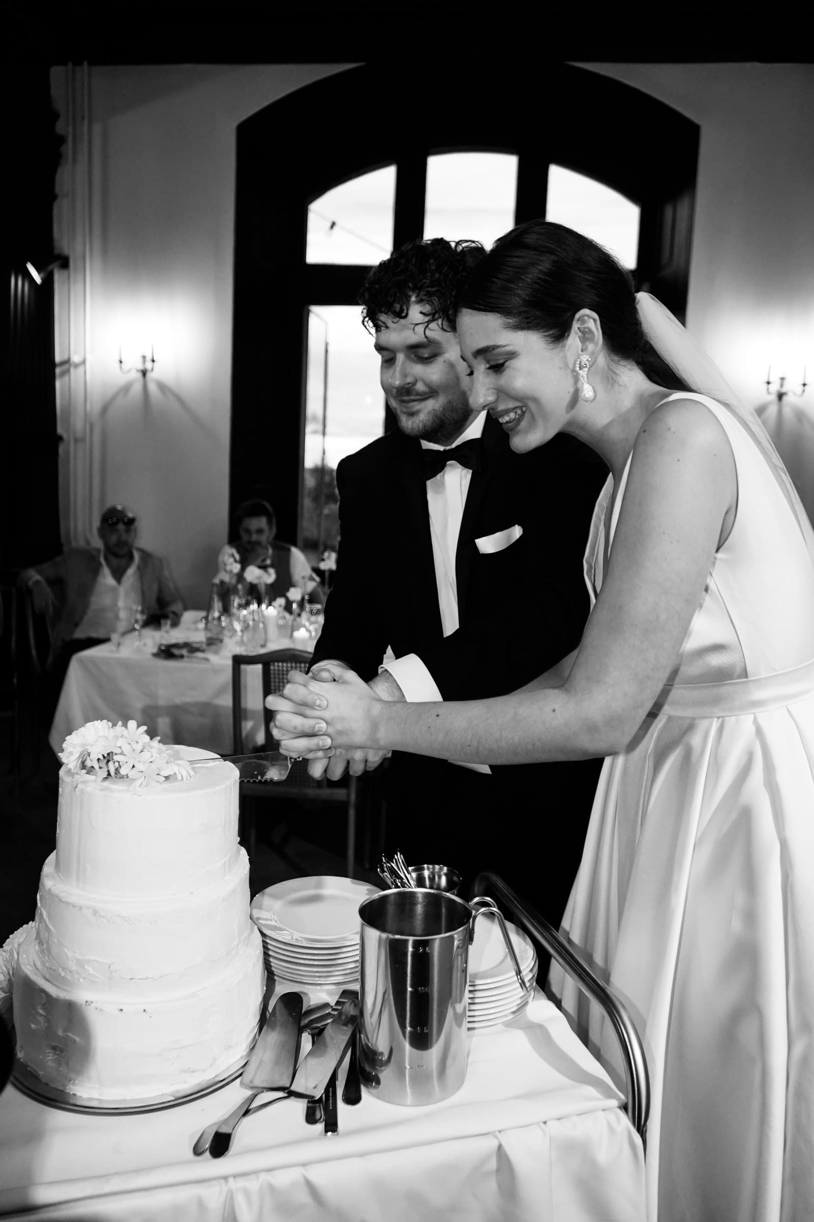 Black-and-white photograph of the wedding couple cutting their cake.