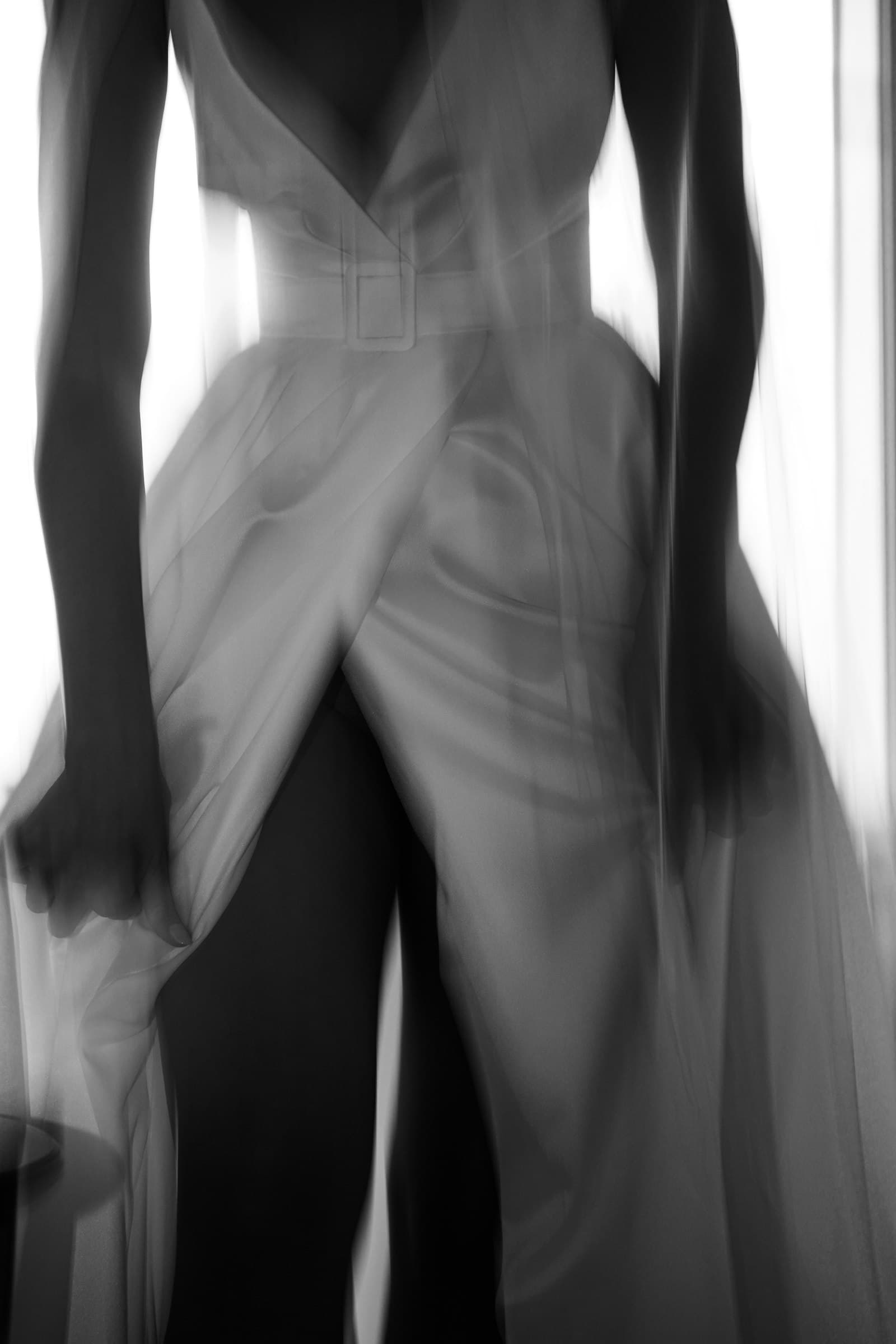 Detail of the wedding dress in soft window light, in black and white.