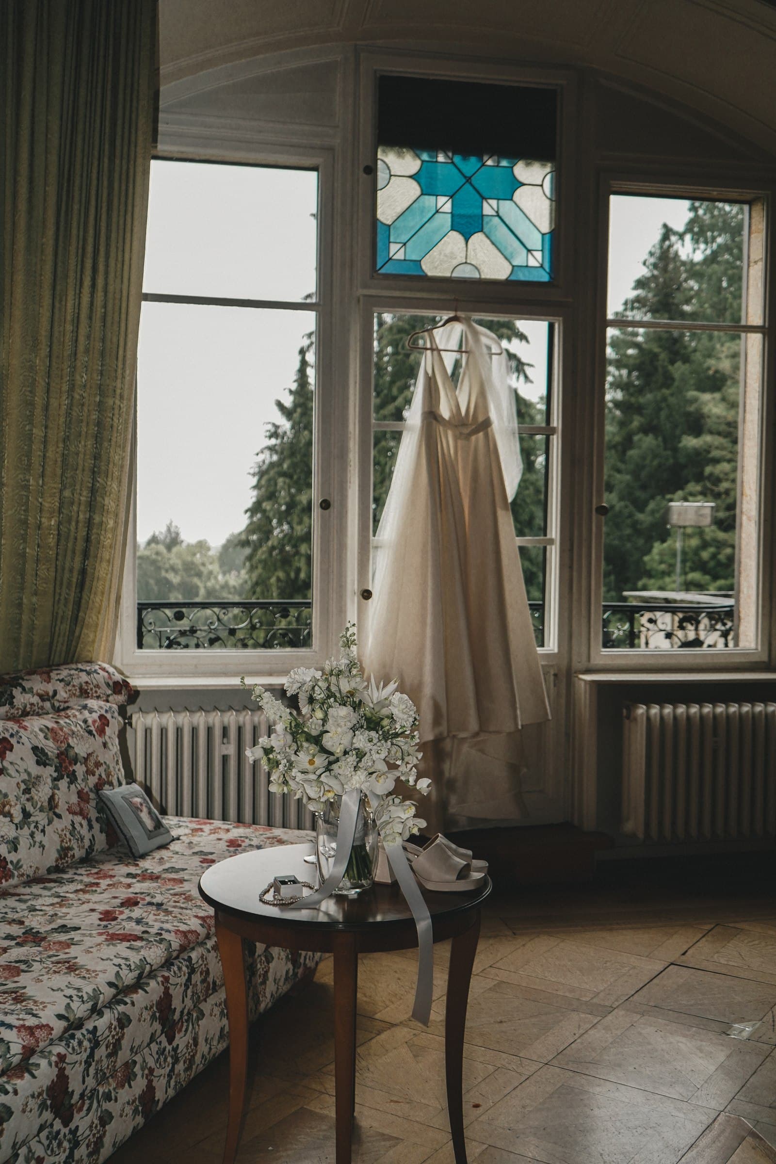 Wedding dress hanging in front of a tall window.