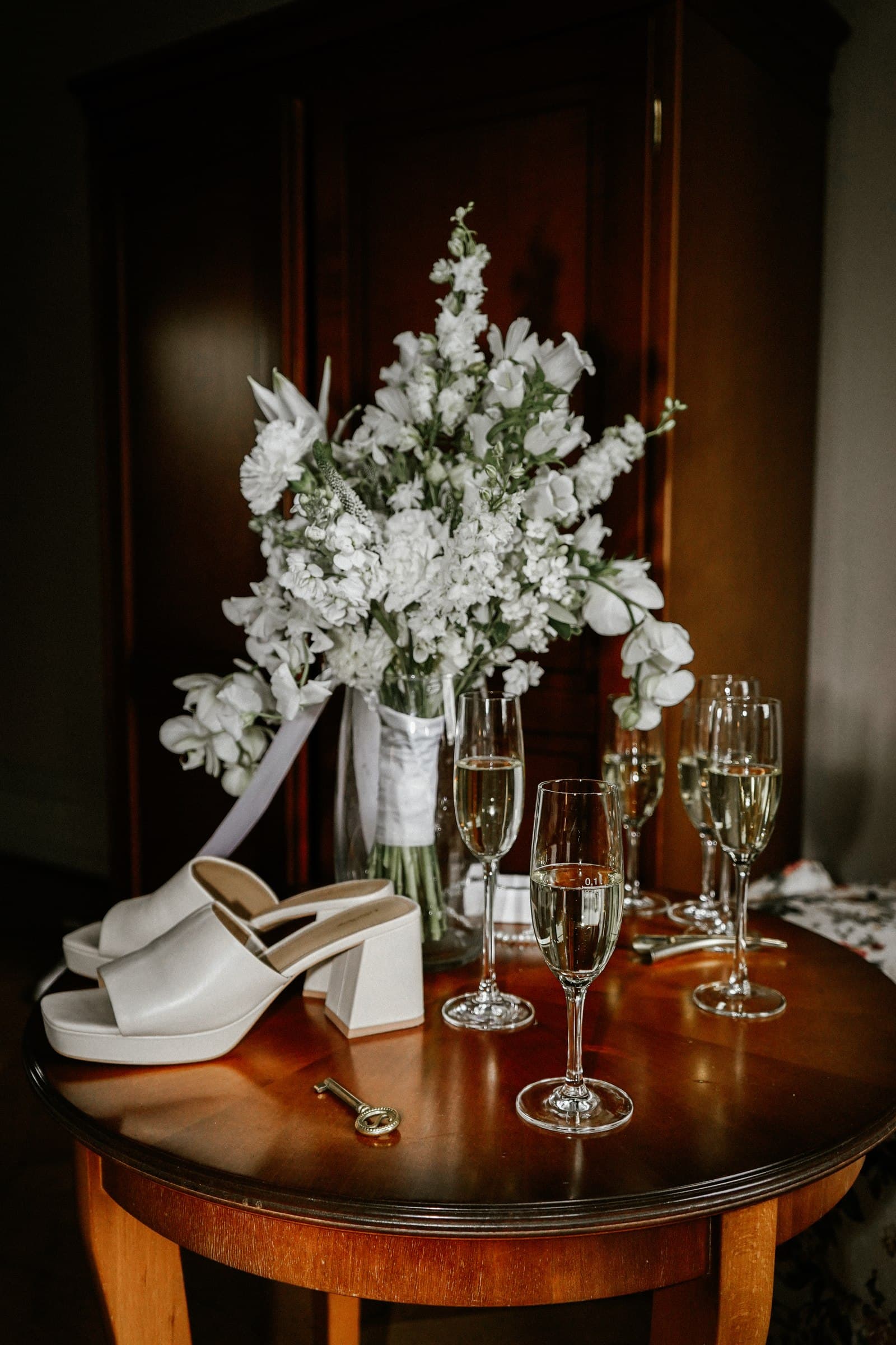 Flowers and glasses arranged on a table in warm light.