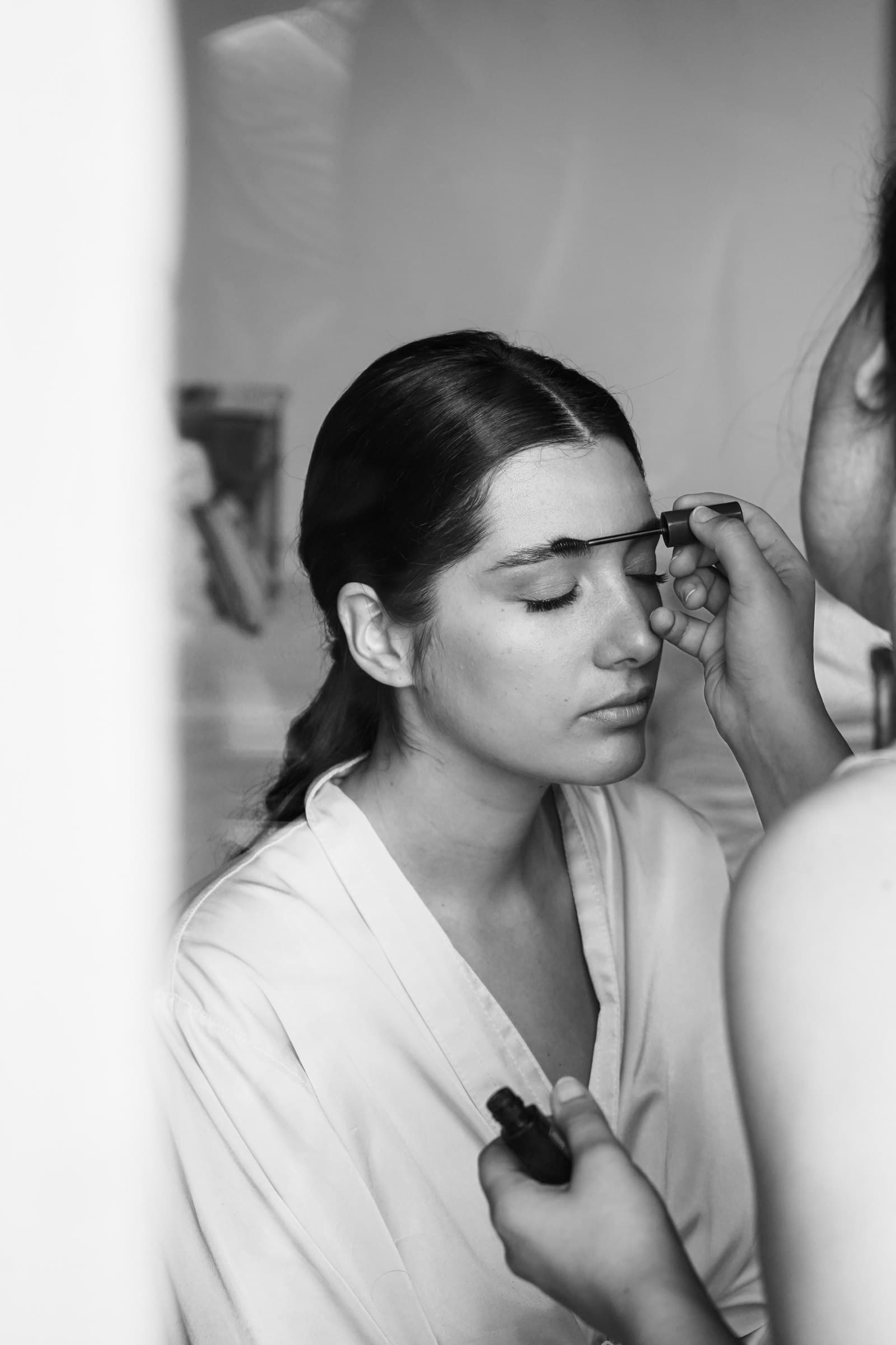 Black-and-white portrait of the bride during make-up preparations.